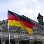 German national flag waving in front of the Reichstag building in Berlin, a symbol of democracy.